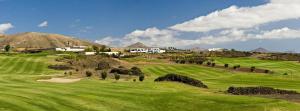 a green golf course with mountains in the background at Apartamento Filla in Puerto del Carmen