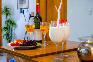 a table with three glasses of wine and a plate of fruit at Voulias Αpartments in Kini