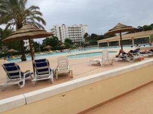 - un groupe de chaises longues et de parasols à côté de la piscine dans l'établissement Apartamento Comunidades Lusiadas, à Portimão