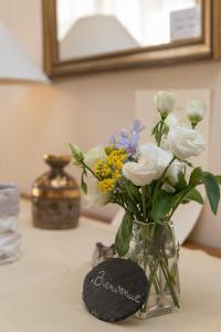 un vase rempli de fleurs blanches et bleues sur une table dans l'établissement La Boudrie, à Avranches