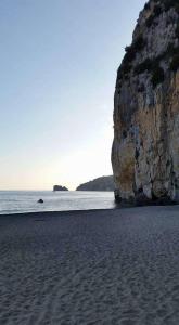 a beach with a large rock and the ocean at La Via Del Mare in Palinuro +10 photos