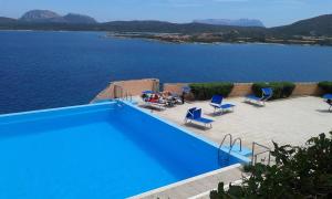 a blue swimming pool with a view of the water at Ladumar Sardinia in Porto Rotondo