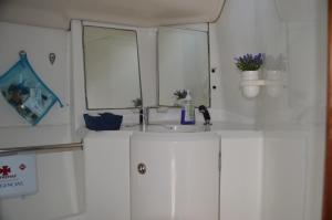W białej łazience znajduje się umywalka i lustro. w obiekcie Noite a bordo c/PA em veleiro -rio Douro w mieście Vila Nova de Gaia