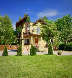 a yellow house with a porch and a yard at Napospatak Apartmanház in Orfű