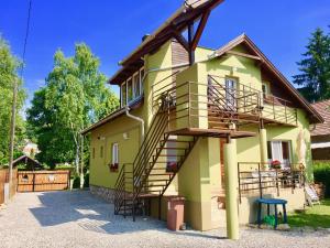 a yellow house with stairs on the side of it at Napospatak Apartmanház in Orfű