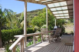 une terrasse couverte en bois avec une table et des chaises. dans l'établissement Hot Water Beach Surf Sound Cottage, à Hotwater Beach