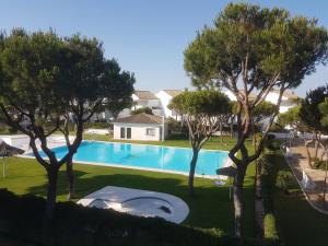 a swimming pool with trees in front of a house at Sancti Petri Marinero in Chiclana de la Frontera