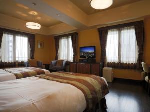 a hotel room with two beds and a flat screen tv at Hotel Monterey La Soeur Osaka in Osaka