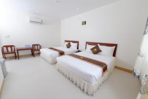 2 Betten in einem Zimmer mit weißen Wänden in der Unterkunft Bong Sen Xanh Hotel in Cao Lãnh