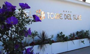 a sign on the side of a building with purple flowers at Torre Del Sole in Terracina