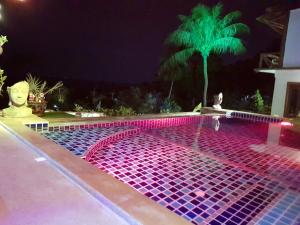 a swimming pool at night with pink and purple lights at Moonstone Studio in Haad Rin