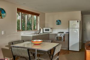 a kitchen with a table and a white refrigerator at Akaroa on the Beach in Akaroa