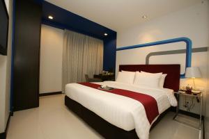 a bedroom with a large bed with a red and white blanket at FX Hotel Metrolink Makkasan in Bangkok