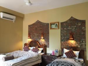 a bedroom with two beds and a brick wall at Chautari Garden Resort in Sauraha