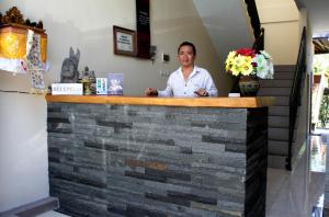 a man sitting at a bar in a restaurant at Dewi Ayu Accommodation in Ubud