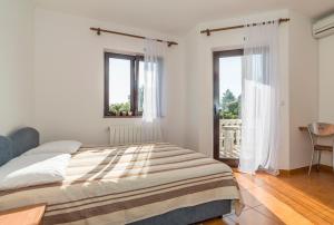 a white bedroom with a bed and two windows at Apartments Vienna in Zambratija