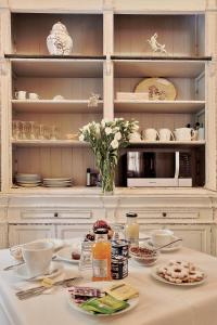 a white kitchen with a table with plates and flowers at Chiaro Di Luna viale Italia in Sassari