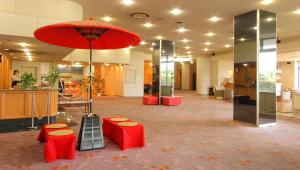 a lobby with red stools and a red umbrella at Hotel Hana Isawa in Fuefuki