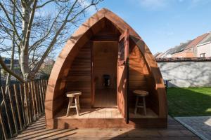 uma casa de hobbit de madeira com dois bancos num deque em Sekowa-lodge em Geraardsbergen