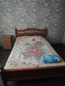 a bed with a flowered bedspread with roses on it at Apartment in Mikrorayon 18, 11 in Zhlobin
