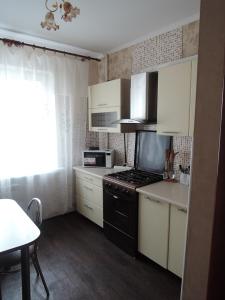 a kitchen with white cabinets and a black stove at Apartment in Mikrorayon 18, 11 in Zhlobin