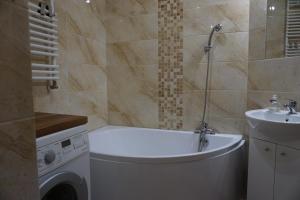 W łazience znajduje się wanna, umywalka i pralka. w obiekcie Apartament ORANGE Warmia Towers w Olsztynie +37 zdjęć
