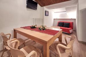 a dining room table with chairs and a red couch at Appartamenti Carlotta in Arabba