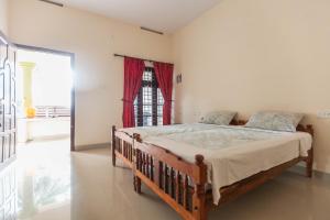 a bedroom with a wooden bed in a room with a window at Mad about Coco Yoga & Beach Retreat in Varkala