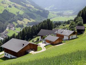 un grupo de edificios en una colina con un campo verde en Huberhof, en San Giovanni in Val Aurina