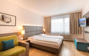 a hotel room with a bed and a chair at Hotel City in Villach