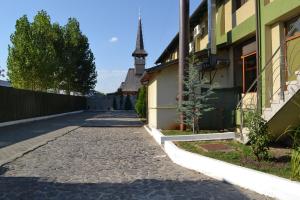a cobblestone street next to a building with a tower at Motel Mesterul Manole in Curtea de Argeş