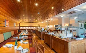 a restaurant with a long bar with wooden tables at Hotel City in Villach