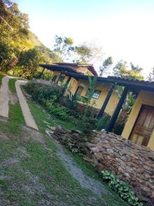 a house with a stone wall next to a road at Ouro Grosso Chales in Iporanga