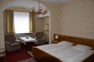 a bedroom with a bed and a chair and a window at Pension Cecilie in Braunlage