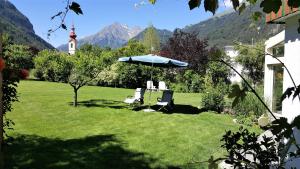 twee stoelen en een paraplu in een tuin met bergen bij Haus Salzmann in Pfunds
