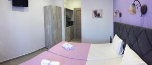 a bedroom with a pink and white bed with towels on it at Studios Nopi-Zoi in Skiathos Town