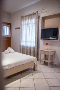 a bedroom with a bed and a flat screen tv at Aloni Studios & Apartments in Athanion