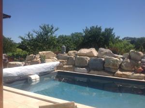 a swimming pool with a retaining wall and a rock wall at Le sang des vignes in Monbazillac