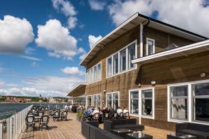 a building with people sitting on a patio next to the water at Strandpiren Hotell in Hudiksvall