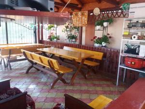 a dining room with a wooden table and benches at Vila MariCris in Tuzla