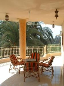 a porch with three chairs and a table and a column at Home Sweet Home Luxor Apartments in Luxor