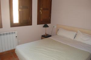 1 dormitorio con 1 cama y 1 lámpara en una mesa en casa sampietro 2, en Alquézar