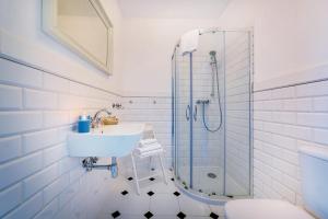 a white bathroom with a sink and a shower at Stare Sady Chillout Rooms "Pod Jabłoniami" in Mikołajki