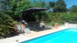 een groep stoelen en een parasol naast een zwembad bij Chambres d'Hotes des Ecureuils in Lanton