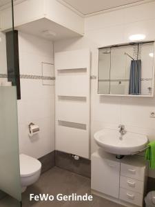 a white bathroom with a sink and a toilet at Ferienwohnung Irmgard und Ferienwohnung Gerlinde in Waldbrunn