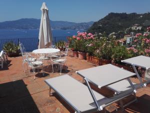 d'une terrasse avec des tables, des chaises et un parasol. dans l'établissement Casa Monteprato, à Zoagli