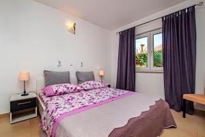 ein Schlafzimmer mit einem großen Bett mit rosa Bettwäsche und einem Fenster in der Unterkunft Dietro la grotta in Rovinj