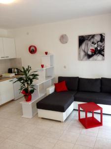ein Wohnzimmer mit einem schwarzen Sofa und einem roten Stuhl in der Unterkunft Villa Jasmin in Bol