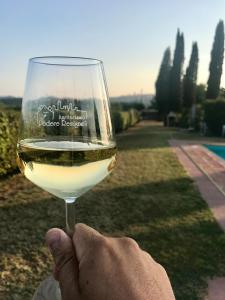 une personne détenant un verre de vin blanc dans l'établissement Podere Remignoli, à San Gimignano