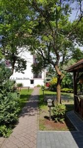 a walkway through a park with a tree and a building at Pensjonat Tadeusz i Apartamenty w Darłówku in Darlowko